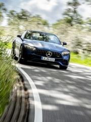 A dark Mercedes-AMG drives on a curved country road towards the viewer